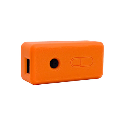 An orange rectangular protective case with rounded corners, featuring a side port, a circular hole, and an embossed power switch, shown on a plain white background.