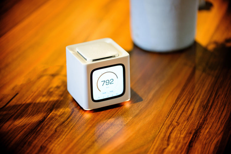 Bitcube on a warm wooden desk beside a mug
